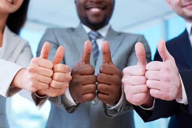 Group of happy workmates showing thumbs up