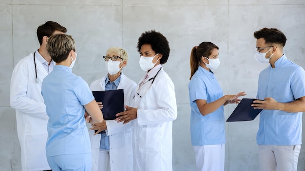 Free Photo group of healthcare workers with protective face masks talking at hospital hallway