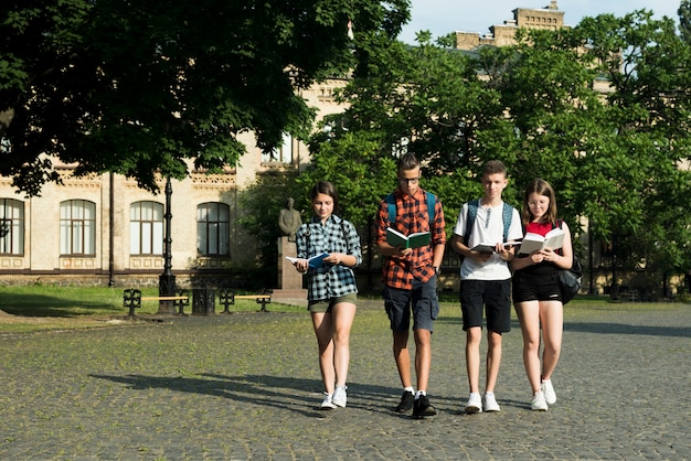 Free photo group of highschool students reading while walking