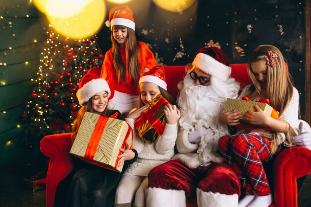 Group of kids sitting with santa and presents on christmas eve