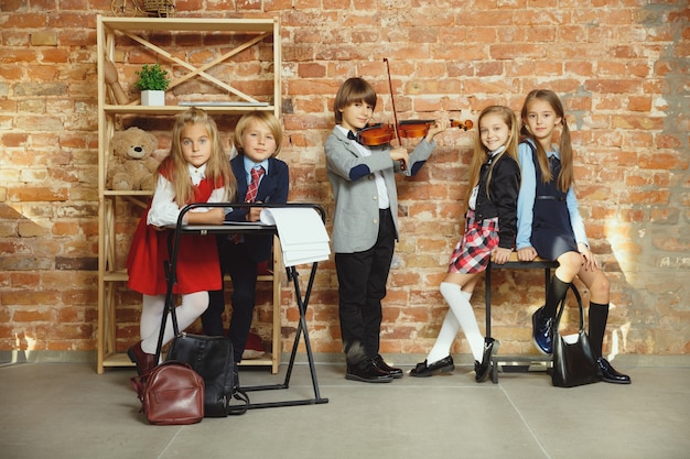 Free photo group of kids spending time after school together. handsome friends resting after classes before start of doing homework. modern loft interior. schooltime, friendship, education, togetherness concept.