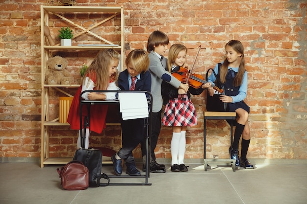 Free photo group of kids spending time after school together. handsome friends resting after classes before start of doing homework. modern loft interior. schooltime, friendship, education, togetherness concept.