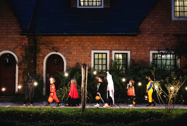 Free photo group of kids with halloween costumes walking to trick or treating