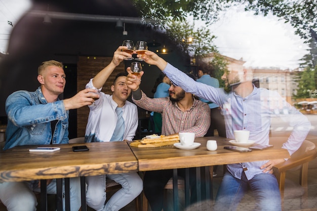 Free photo group of male friends raising toast in the restaurant