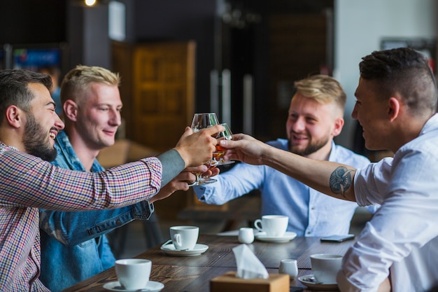 Free photo group of male friends sitting in the restaurant toasting glasses of drinks