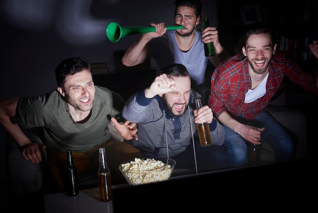 Group of men drinking beer and watching soccer on TV