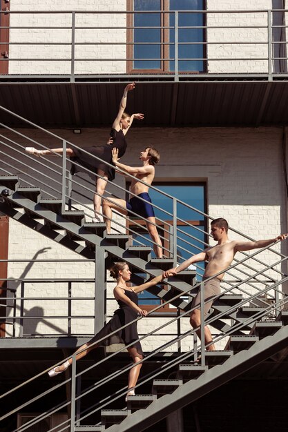 The group of modern ballet dancers performing on the stairs at the city