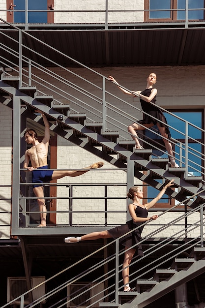 The group of modern ballet dancers performing on the stairs at the city