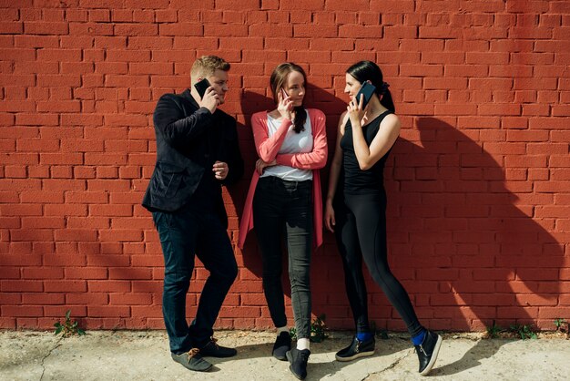 Group of people calling on phones leaning on wall