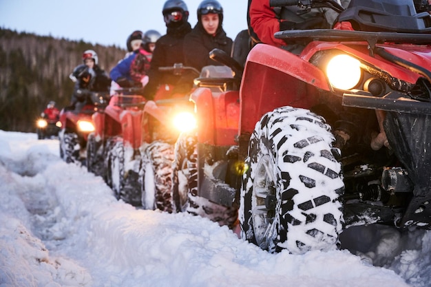 Group of people driving quad bikes on snowy road