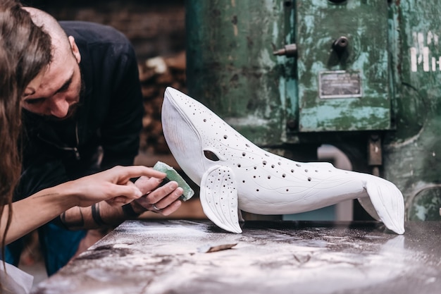 Free photo group of people enjoying favorite job in workshop. people carefully work on ceramic whales