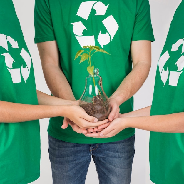 Group of people holding plant in hands together