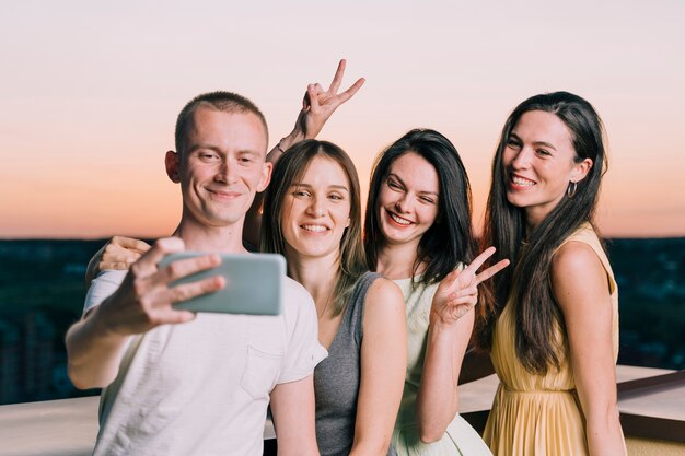 Group of people taking selfie at rooftop party