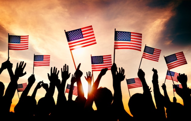 Group of People Waving American Flags in Back Lit