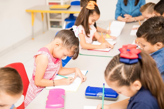 Group of preschool kids working on a writing assigment in a classroom