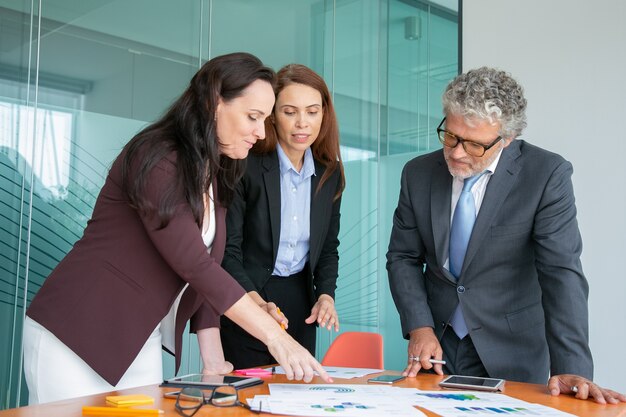 Group of professionals analyzing paper reports with charts and graphs