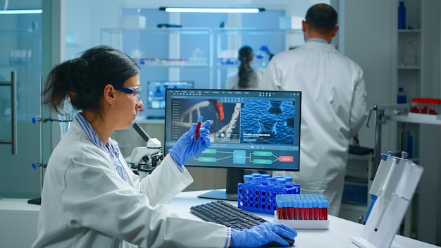 Group of scientists wearing lab coat working in laboratory while examining biochemistry sample in test tube and scientific instruments