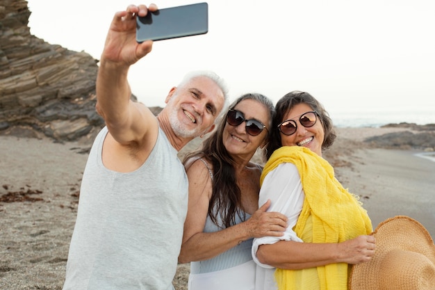 Group of senior friends taking selfie with smartphone on the beach