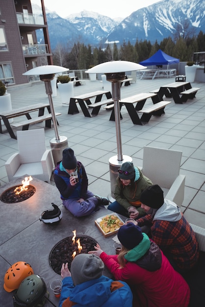 Free Photo group of skiers rubbing their hands near fireplace