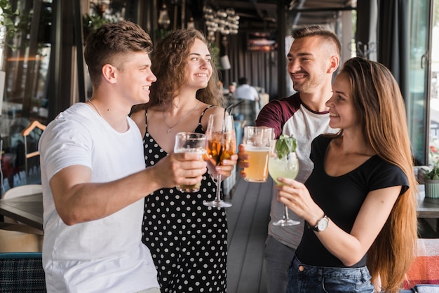 Free Photo group of smiling friends holding alcohol drinks set making toast