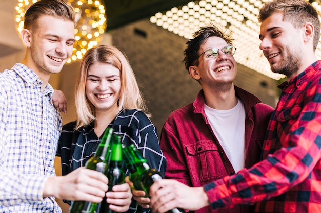 Free photo group of smiling friends toasting the beer bottles in pub