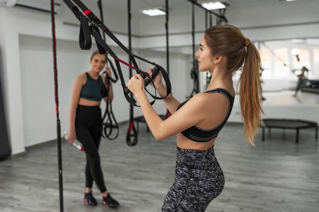 Group of sports people are training outdoors with TRX