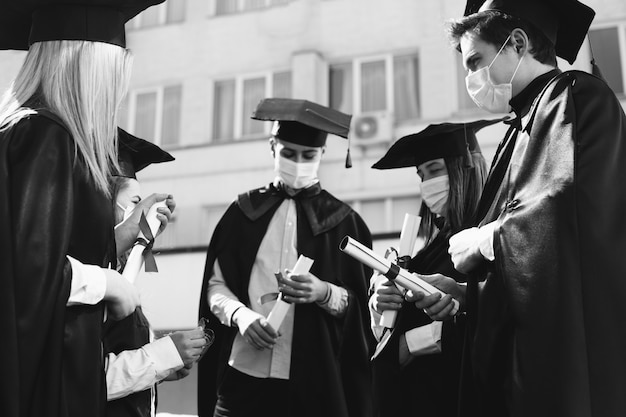 Free photo group of students celebrating graduation together and wearing face masks