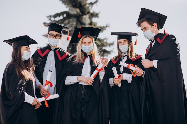 Free photo group of students celebrating graduation together and wearing face masks