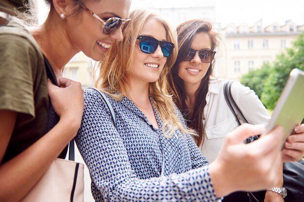 Group of stylish women enjoying in the city and using a digital tablet