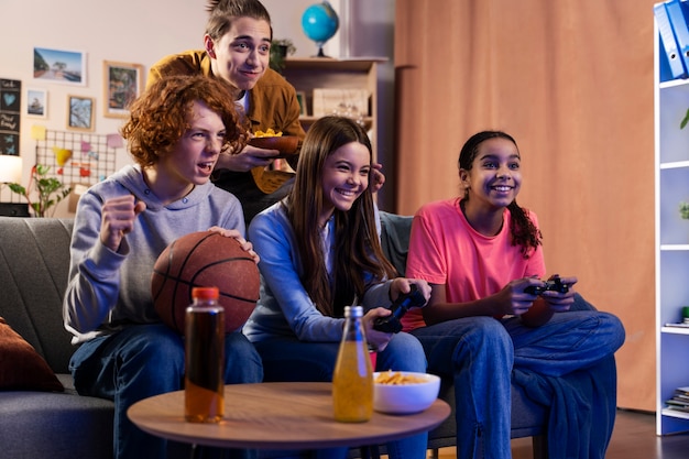 Group of teenage friends playing video games together at home