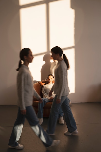 Free photo group of women in sweaters and jeans posing for minimalistic portraits in window shadow