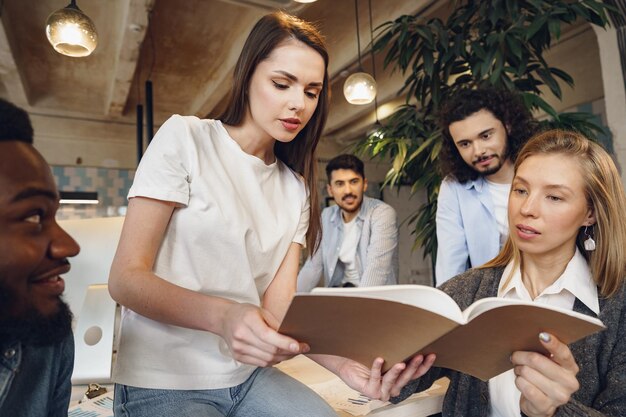 Group of young business people discussing documents during meeting in office