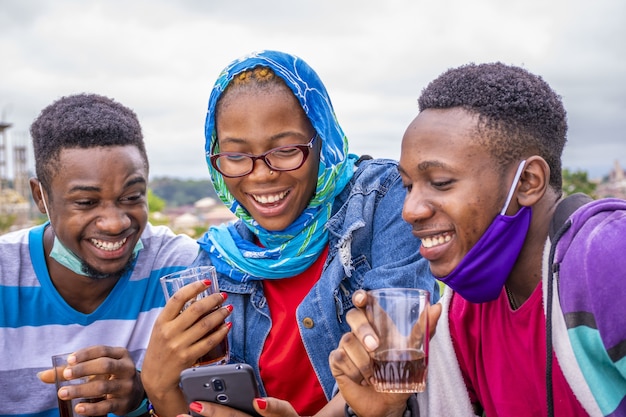 Group of young friends drinking wine and using their phones at a park