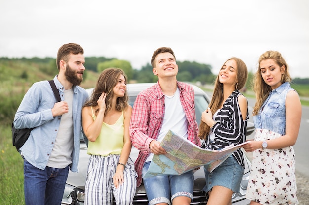 Group of young friends standing in front of car at outdoors