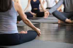 Free photo group of young sporty people sitting in lotus pose, closeup