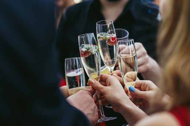 Guests clang glasses of champagne with delicious strawberries