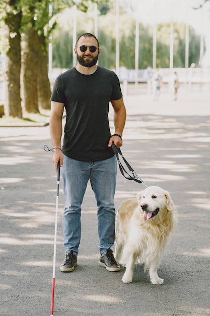 Free Photo guide dog helping blind man in the city. handsome blind guy have rest with golden retriever in the city.