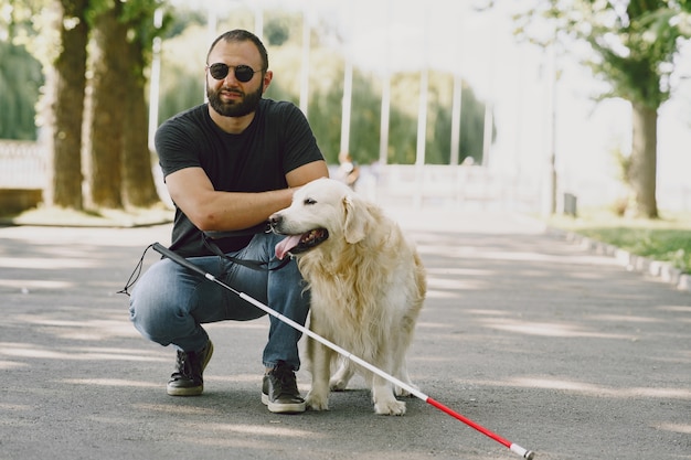 Free Photo guide dog helping blind man in the city. handsome blind guy have rest with golden retriever in the city.