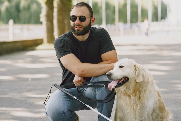 Free Photo guide dog helping blind man in the city. handsome blind guy have rest with golden retriever in the city.