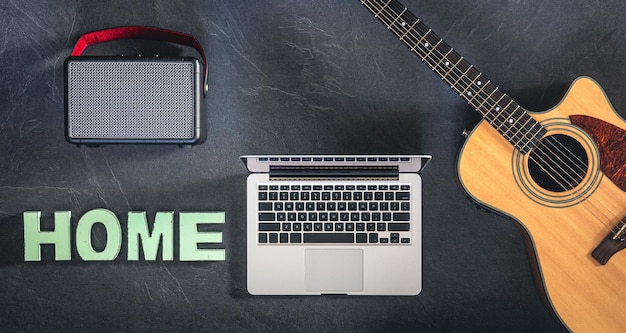 Free Photo guitar laptop speaker and word home on a black background top view