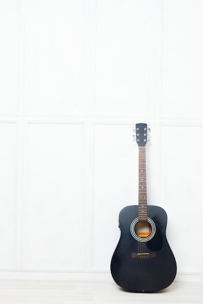 Free photo guitar propped in front of a white wall