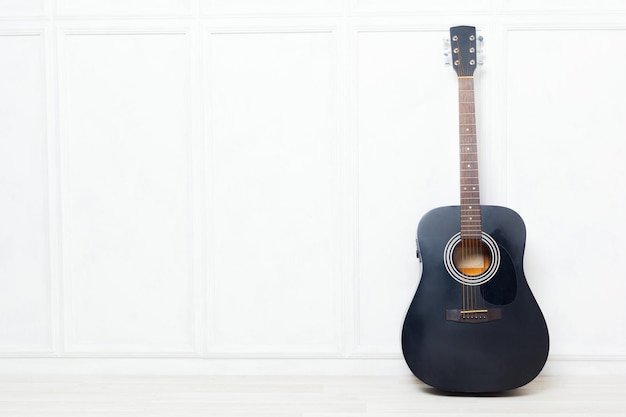 Free photo guitar propped in front of a white wall