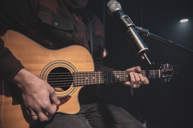 The guitarist plays an acoustic guitar with a capo in front of a microphone