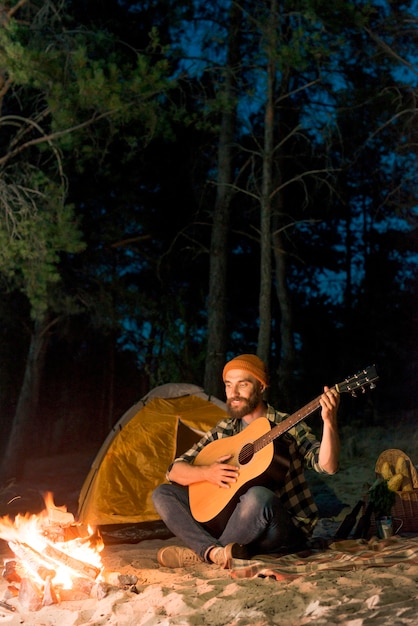 Free Photo guitarist singing at night by a tent with a campfire