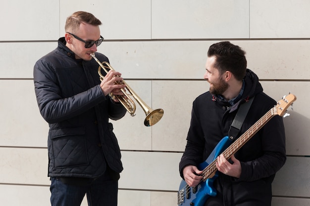 Free photo guitarist watching trumpet player play his instrument