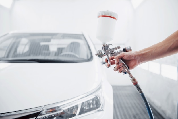 gun with paint in the hands of a man to paint a car