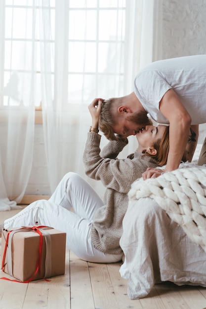 The guy on the bed kisses a woman who sits on the floor