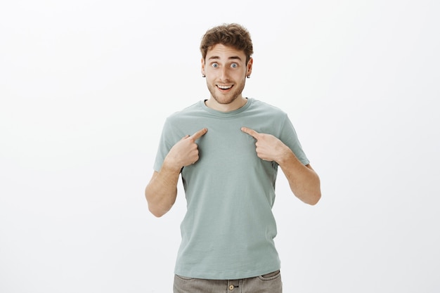 Free photo guy cannot believe in his luck, being picked as winner. portrait of impressed happy and excited attractive man in casual t-shirt, smiling broadly and gasping from surprise