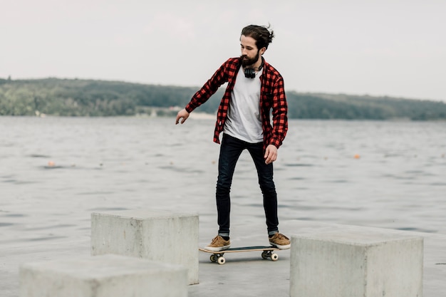 Guy in flannel on skateboard by a lake