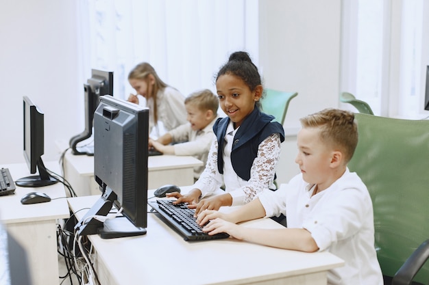 Free Photo guy and the girl are sitting at the table. african girl in computer science class. kids playing computer games.